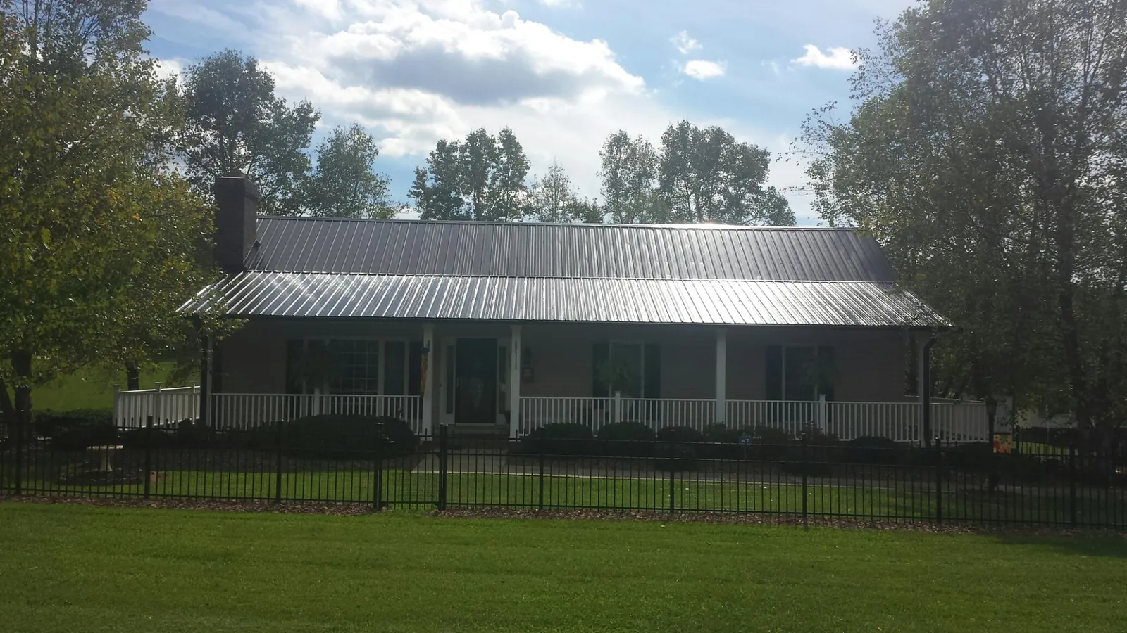 Gray metal roof on a brick ranch with a full width front porch — Gutter Guard Installation work by our crew in Holbrook